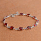 Silver tennis-style bracelet with red oval stones and curved linked chain.