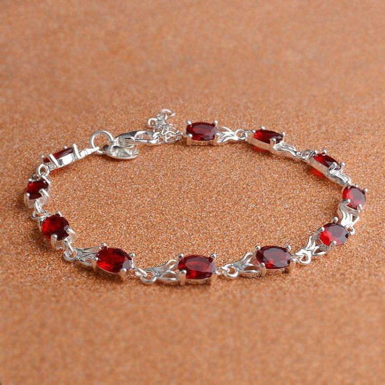 Silver tennis-style bracelet with red oval stones and curved linked chain.