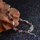 Red stone tennis bracelet with silver linked chain and oval gems on hand.