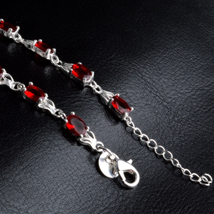 Silver bracelet close-up with red oval stones and lobster clasp end links.