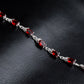 Silver linked bracelet with repeating red oval gemstone settings.