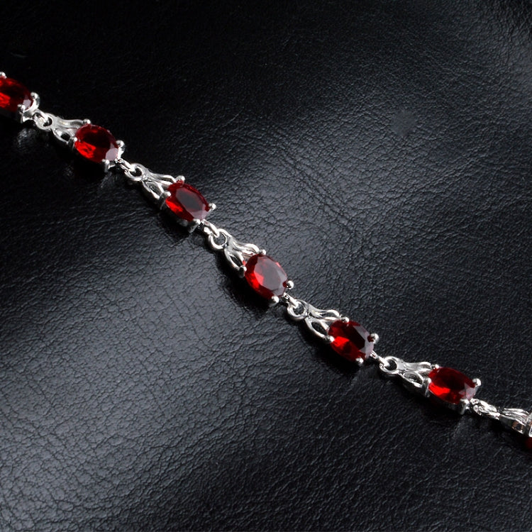 Silver linked bracelet with repeating red oval gemstone settings.