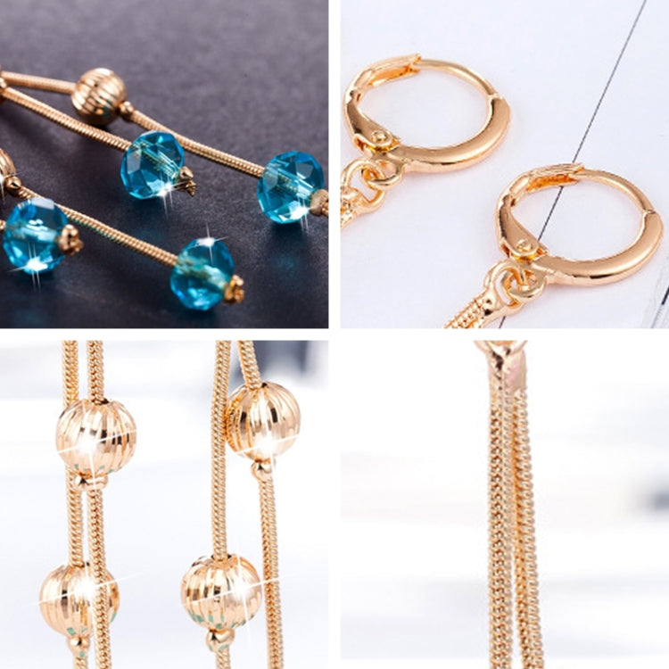Gold-tone tassel earrings with blue and clear crystal bead drops, close-up