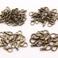 Bronze tone lobster claw clasps scattered, small loop-and-hook metal connectors