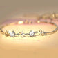 Silver-tone bracelet with round clear stones and flower-link frangipani charms