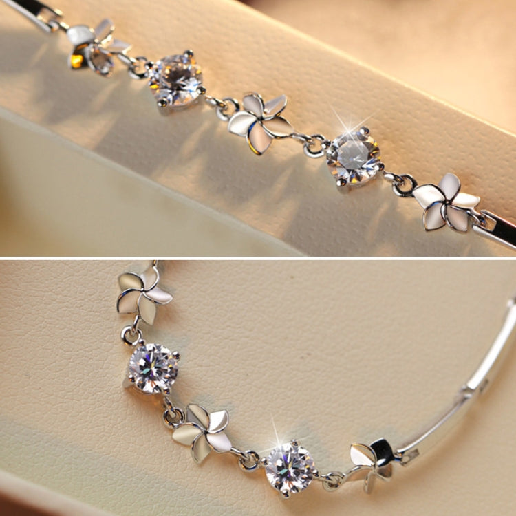 Silver-tone frangipani flower bracelet on wrist with round clear stone centers