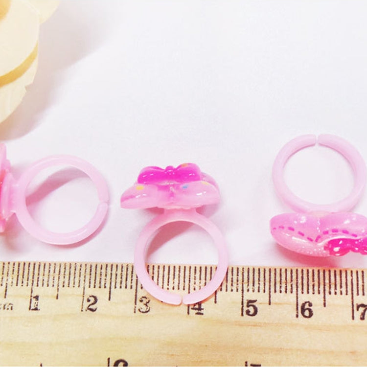 Pink resin kids character rings with heart and bow details, shown with ruler for size
