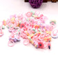Pile of pastel frosted resin kids rings with cartoon flowers, bows, hearts, and animal faces