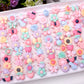Tray filled with frosted resin kids rings in pastel flower, heart, bow, and animal shapes