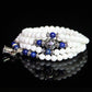 White beaded bracelet with blue bead accents and silver charm detail