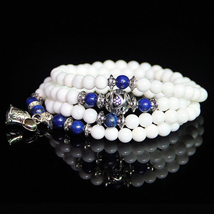 White beaded bracelet with blue bead accents and silver charm detail