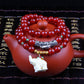 Red beaded bracelet with green accent beads and white animal figurine charm