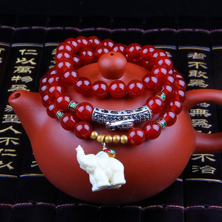 Red beaded bracelet with green accent beads and white animal figurine charm