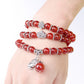 Red beaded bracelet worn on wrist with silver spacer beads and dangling elephant charm