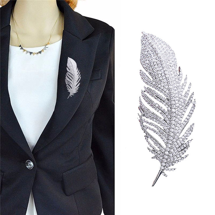 Feather-shaped rhinestone brooch on dark suit lapel