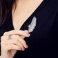 Feather-shaped crystal brooch pinned on navy clothing