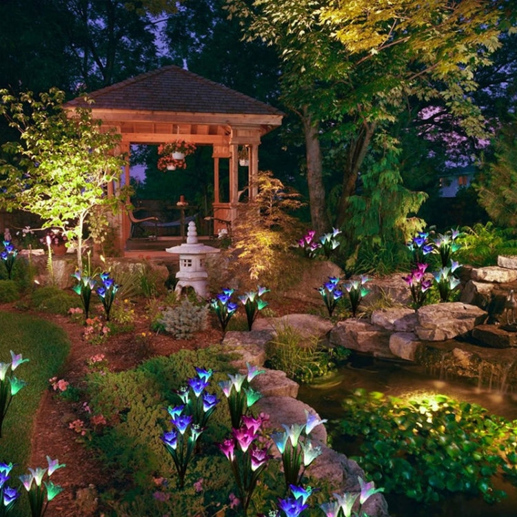 Solar lily LED garden stakes lining a garden bed, multi-color glowing flower heads