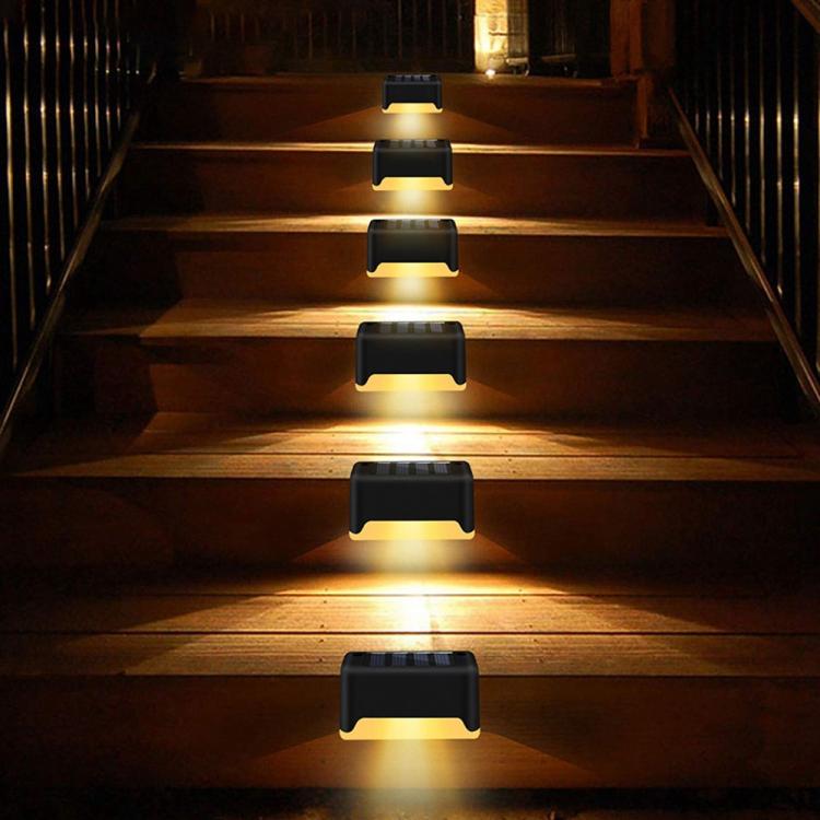 Black solar step lights glowing warm on an outdoor wooden staircase at night.