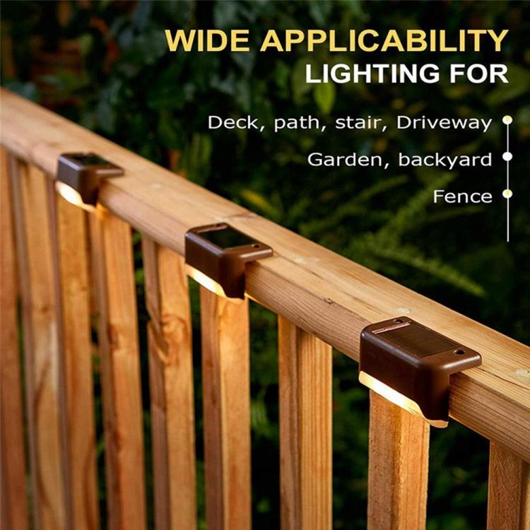 Single black solar railing light mounted on a wooden deck railing, warm LED glow visible.