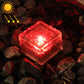 Solar LED buried light cube with red glow through clear textured glass