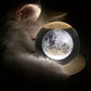 Crystal ball music box night light with moon-like glow on round wooden base.