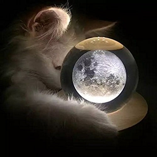 Crystal ball music box night light with moon-like glow on round wooden base.