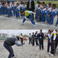 Children playing with a wooden spinning whipping top outdoors on a paved ground