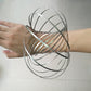 Stainless steel multi-loop spring fidget bracelet held between hands, wire coil visible
