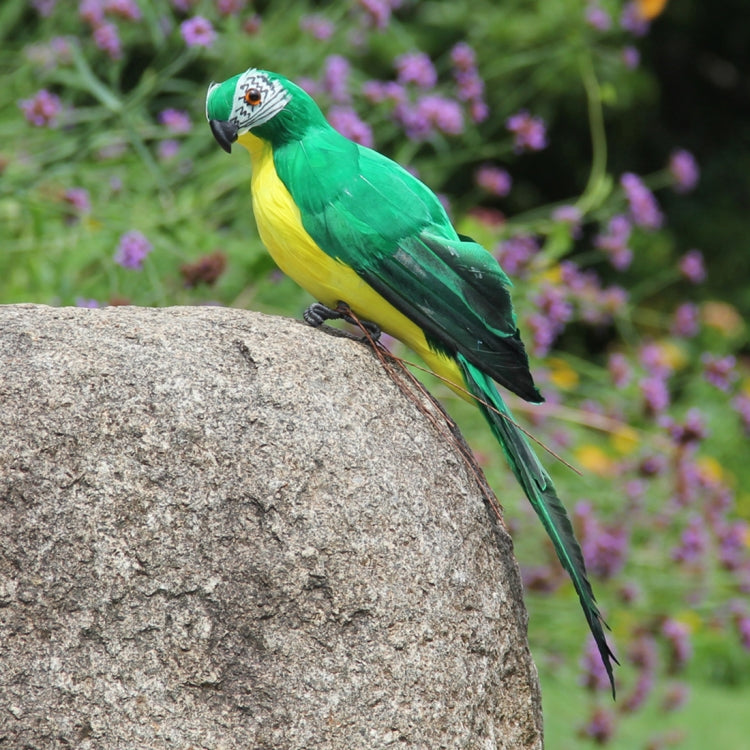 Green simulation parrot decoration perched on a rounded stone, long tail pointing down