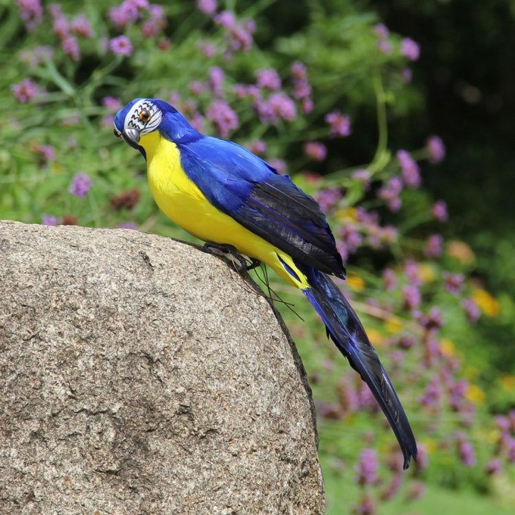 Blue and yellow simulation parrot decoration perched on a rounded stone, angled profile