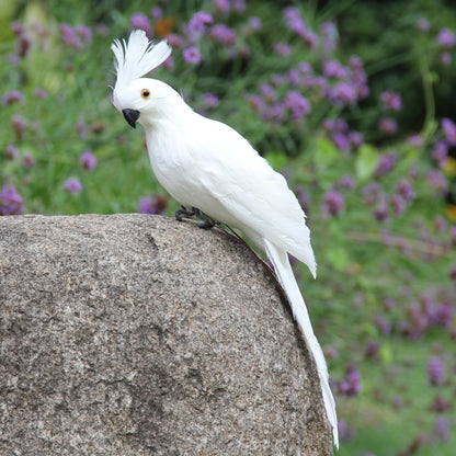 White simulation parrot decoration, perched on a rounded stone, side view with yellow eye