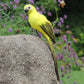 Yellow simulation parrot decoration perched on a rounded stone, standing pose