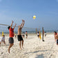 Soft No. 5 volleyball in midair above beach net, white yellow and pink