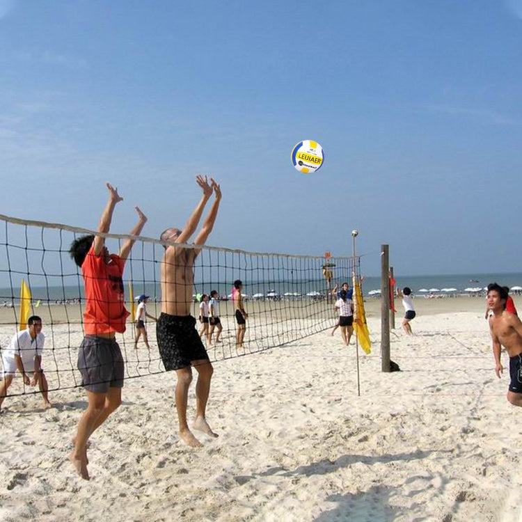 Soft No. 5 volleyball in midair above beach net, white yellow and pink