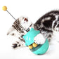 Turquoise cat food tumbler ball toy with dangling teaser stick, shown with cat paws