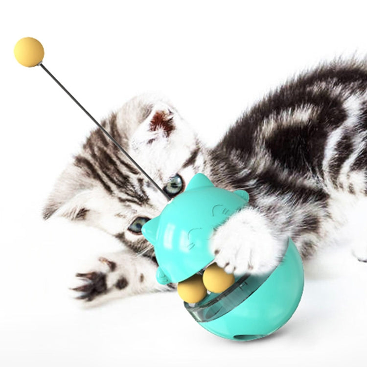 Turquoise cat food tumbler ball toy with dangling teaser stick, shown with cat paws