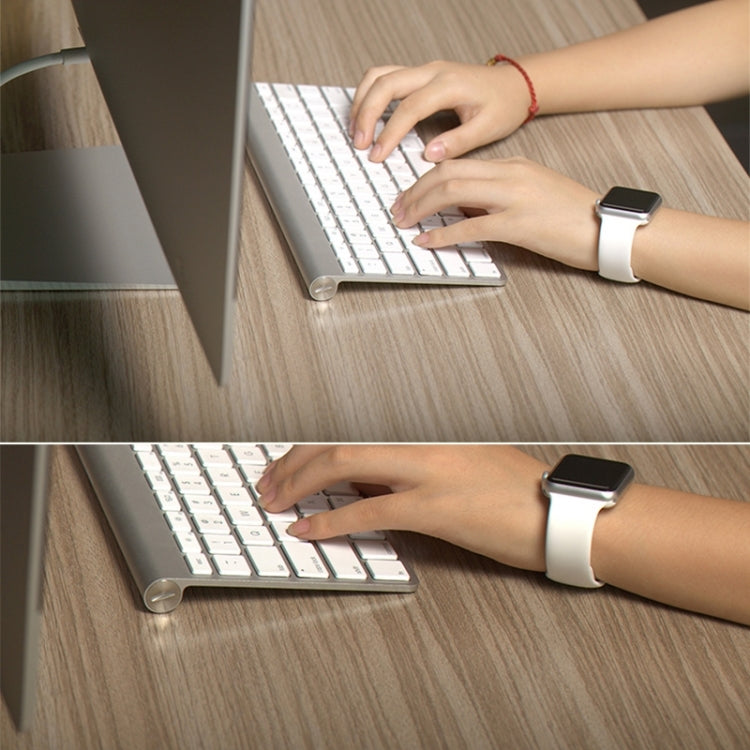 White rubber Apple Watch band with pin-and-tuck closure on wrist while typing, 42mm smartwatch