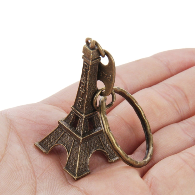 Bronze Eiffel Tower keychain held in hand, showing engraved Paris text and ring