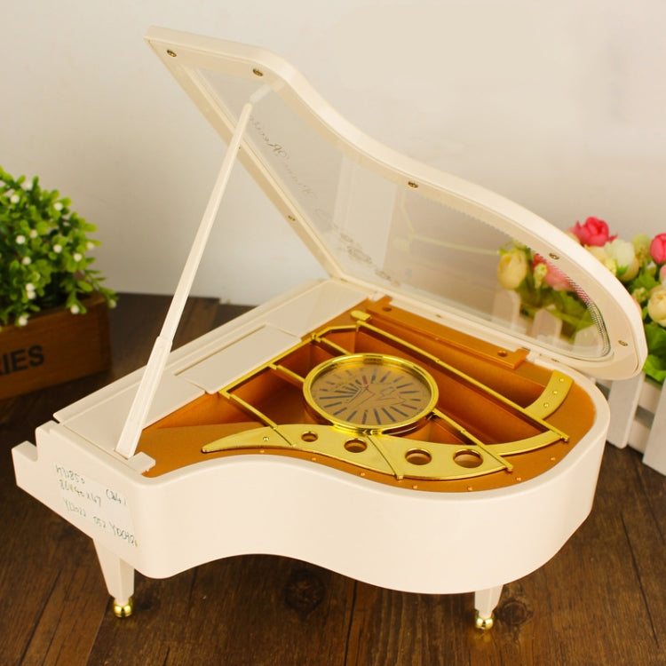 White music box piano with open lid showing golden wheel and internal parts