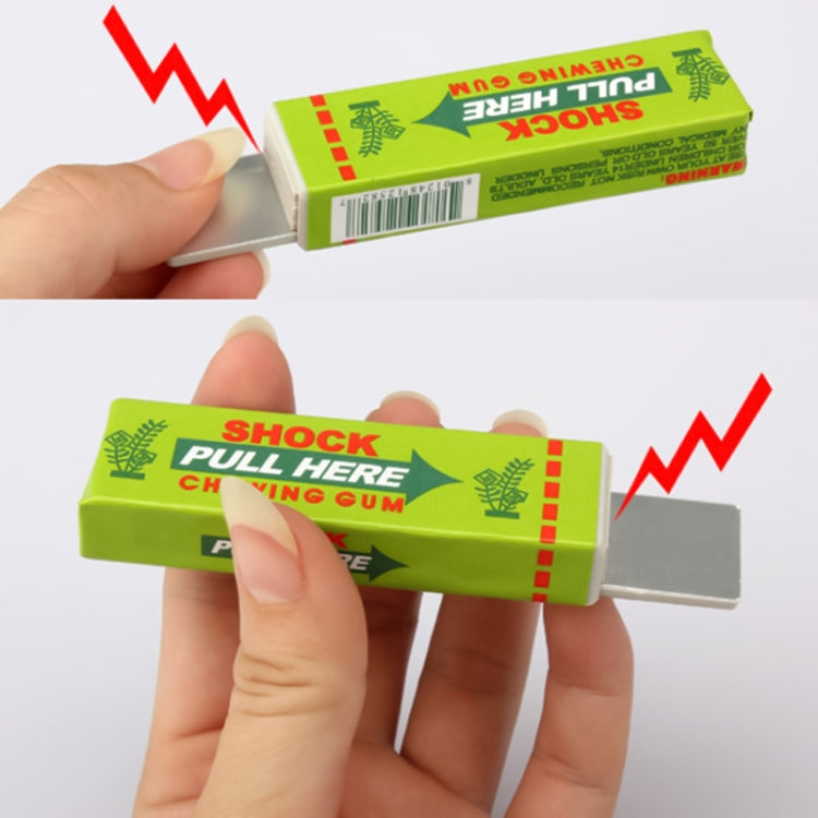 Green shock chewing gum toy being pulled open by hand, gray gum tray visible