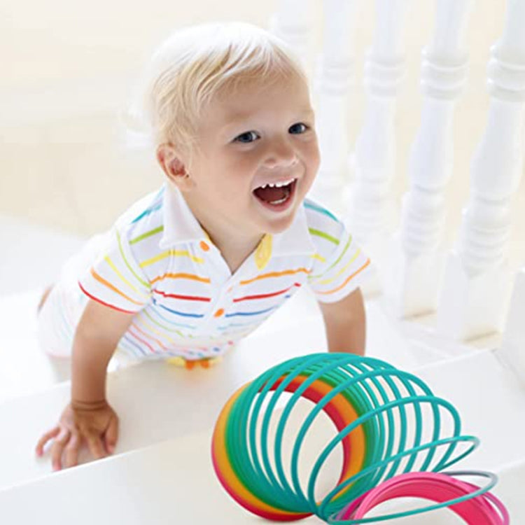 Rainbow spring coil ring toy held by child, teal and green coil with pink accents