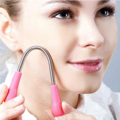 Facial hair remover tool with pink handle and metal spring loop, held in hand