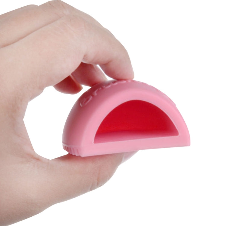 Silicone makeup brush cleaner scrubber held in hand, pink exterior with red interior