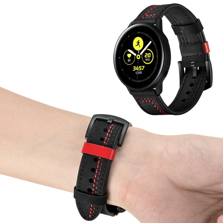 Black leather watch strap with red stitching worn on a wrist over a smartwatch