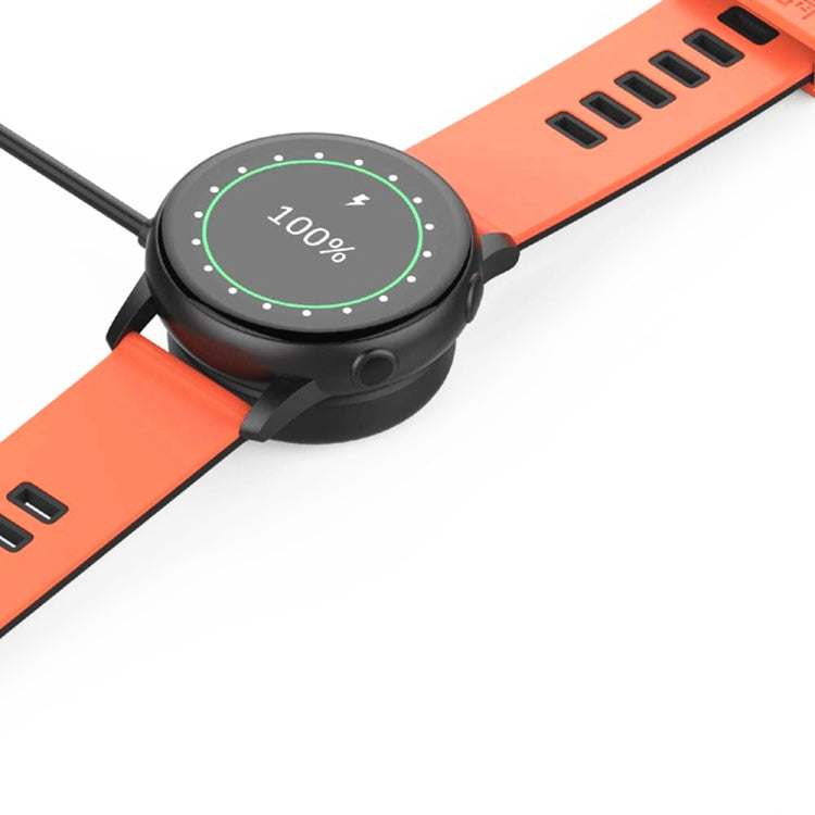 Black magnetic charger dock on orange smartwatch band showing '100%'