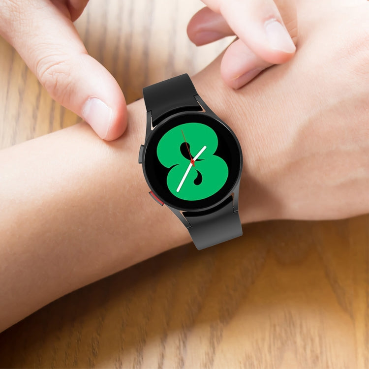 Black silicone smartwatch strap on wrist with green four-leaf clover watch face