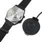 Magnetic charging puck near smartwatch with black strap