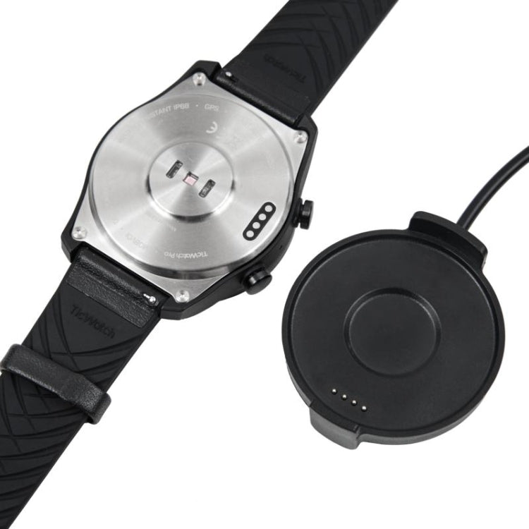 Magnetic charging puck near smartwatch with black strap