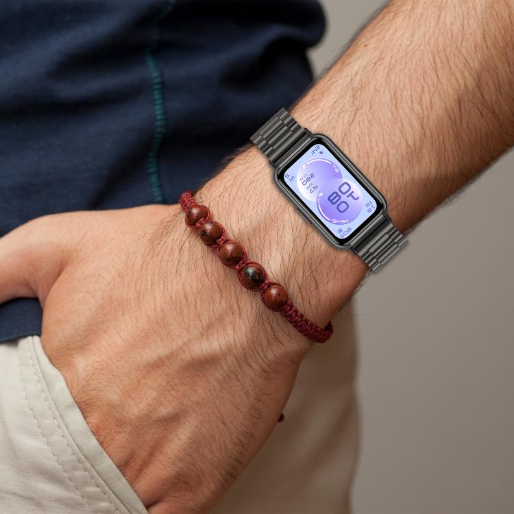 Black stainless steel watch band worn on a wrist with a Huawei fitness watch.
