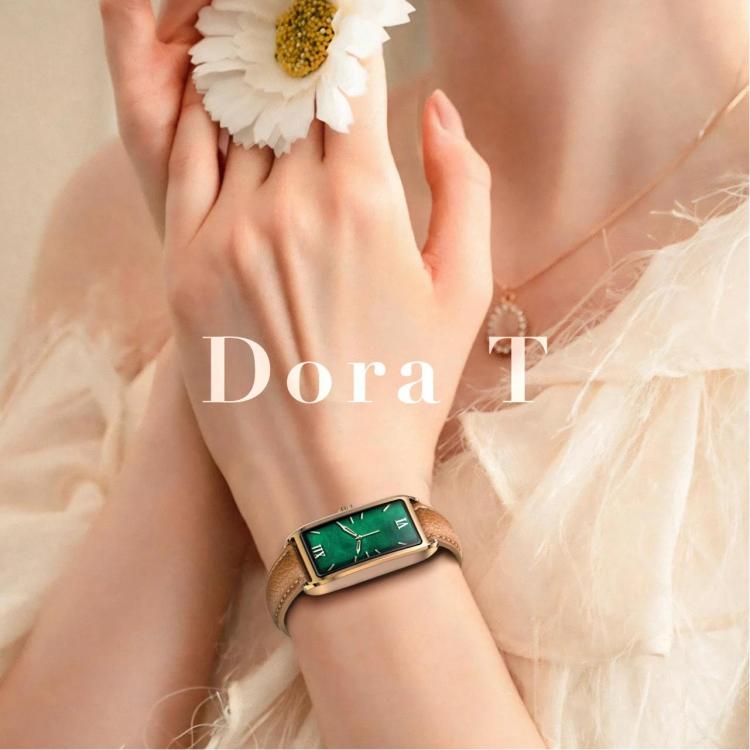 Dora T smartwatch worn on wrist, with a tan strap, gold-tone case and green display.